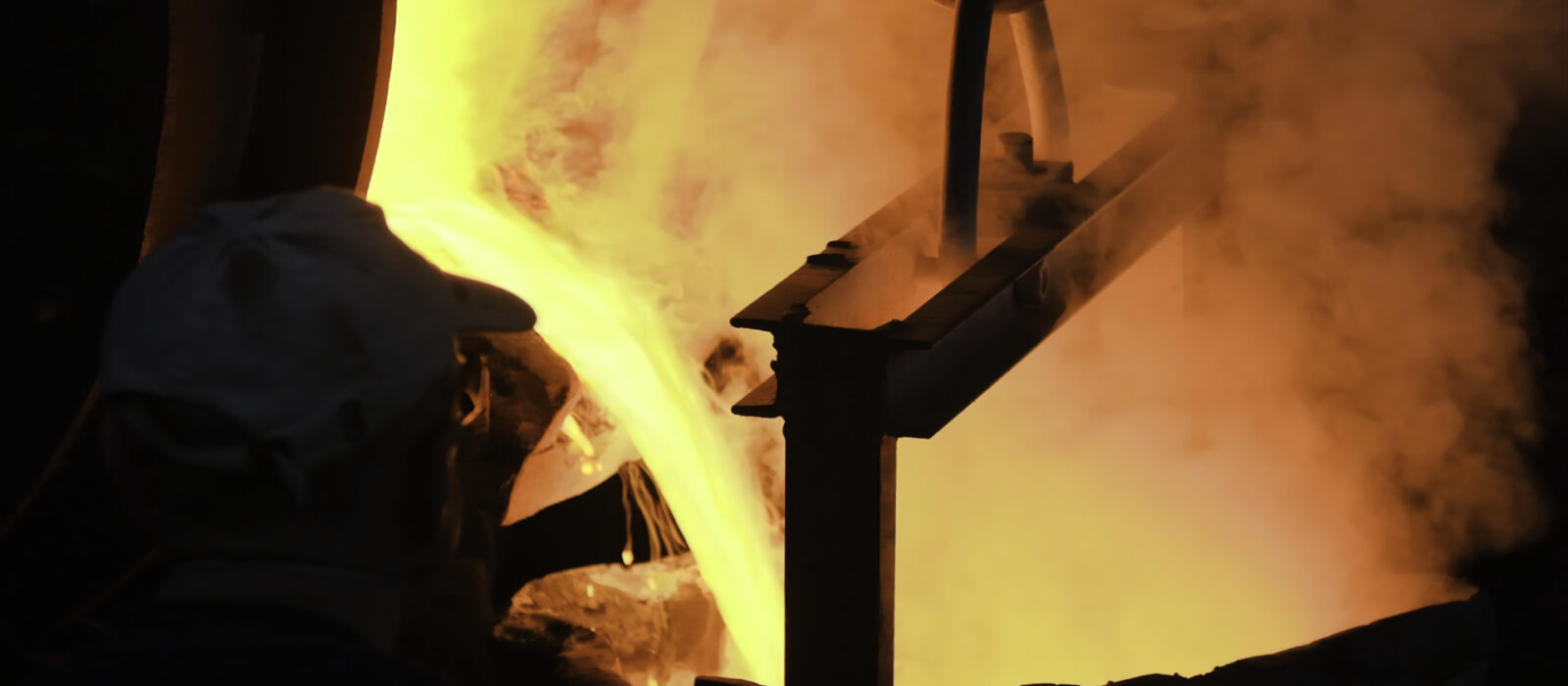 A color image of molten steel pouring at steel plant. Stock footage. Flowing metal at the foundry. Pouring of liquid metal in open hearth workshop.